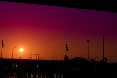 Silhouette cranes against clear sky during sunset