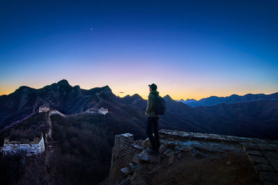 Woman photographing mountains against clear sky