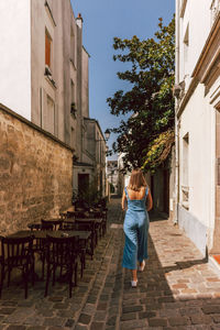 Rear view of woman walking by building