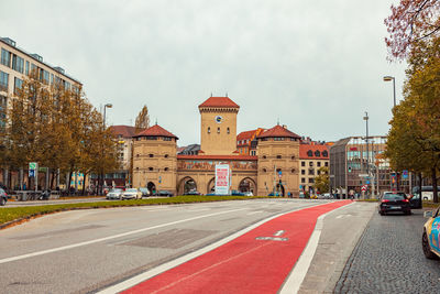 Road by buildings in city against sky