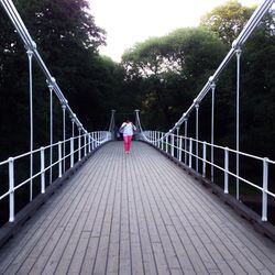 Rear view of woman standing on footbridge