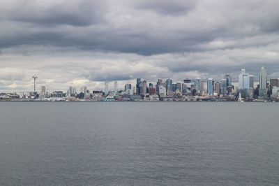 Sea by buildings against sky in city