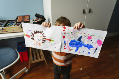 Boy showing drawing in bedroom at home