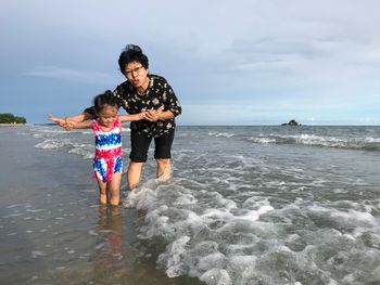 Grandmother playing with cute granddaughter at beach