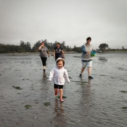 Full length of father and daughter walking on beach