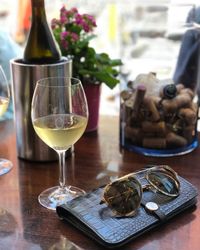 Close-up of wineglass by purse and sunglasses on table