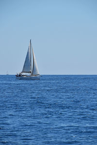 Sailboat sailing on sea against clear sky