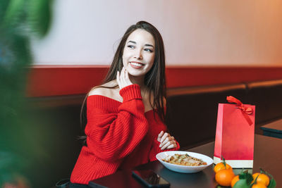 Beautiful smiling young asian woman in red clothes eating asian food in chinese  restaurant