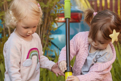 Two passionate girls pumping water with children's pumps from a small pond. close up.