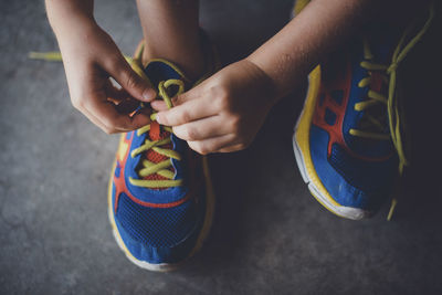 Cropped hands of boy tying shoelace