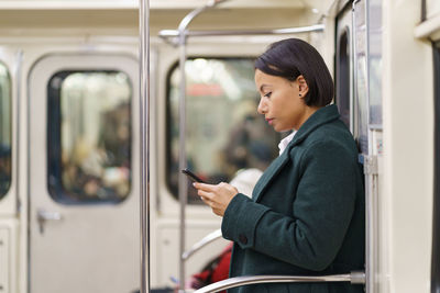 Sad afro american woman with smartphone in subway, tired female office worker using public transport