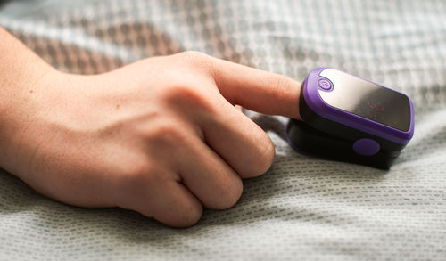 Close up of a hand with a pulse oximeter placed on the finger.