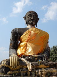 Low angle view of buddha statue against temple against sky in laos. 