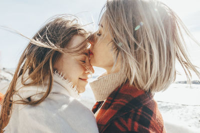 Mother kissing daughter on forehead at beach