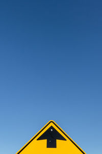 Low angle view of arrow sign against clear sky