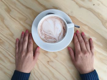 Cropped hands by coffee cup on table