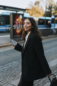 Smiling young woman holding cell phone