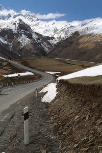 Road by snowcapped mountains against sky