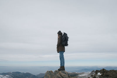 Male hiker standing on mountain against sky