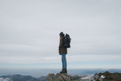 Woman standing on rock against sky