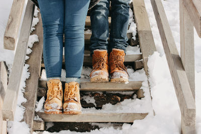 Low section of women standing on snow covered staircase