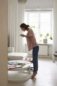 Full length side view of fashion designer photographing fabric at home