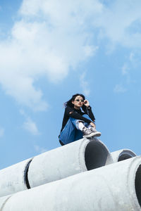 Low angle view of woman sitting against sky