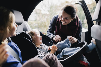 Happy mother tickling daughter sitting in car