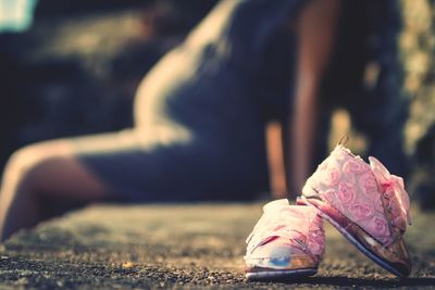 Close-up of baby shoes with pregnant woman sitting in background