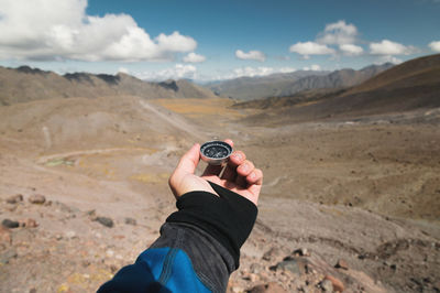 First-person view of a male traveler's hand holding a magnetic compass against the backdrop 