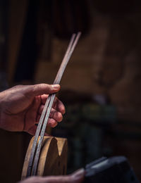 Cropped hand holding sticks in darkroom