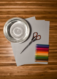 High angle view of coloured pencils, paper, scissors on table for a diy project