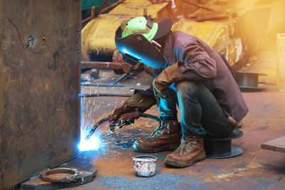 Side view of welder welding metal in factory