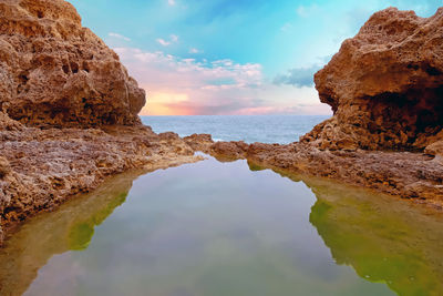 Rock formations by sea against sky