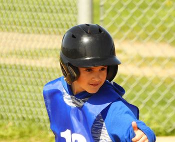 Portrait of boy wearing helmet while gesturing on field