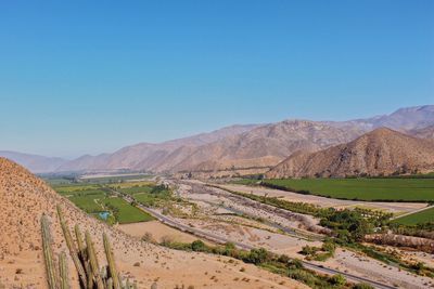 Scenic view of land and mountains against clear blue sky