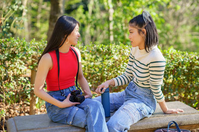 Side view of woman sitting on bench at park