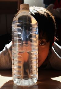 Close-up portrait of boy with water bottle on table