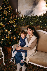Portrait of young woman sitting on christmas tree