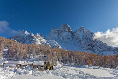 Unrecognizable pair of tourists sitting in front of beautiful winter scenery of mount pelmo, italy