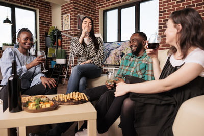 Portrait of friends sitting on sofa at home