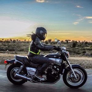 Motorcycle parked on road at sunset