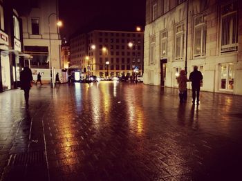 People walking on wet street at night