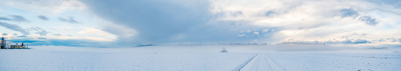 Panoramic view of snow covered landscape against sky