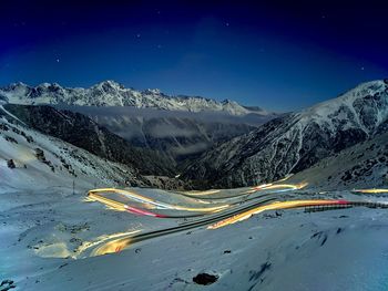 Scenic view of snowcapped mountains against blue sky at night