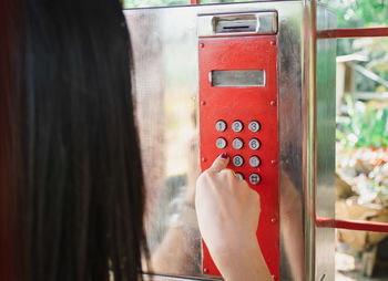 Close-up of woman dialing numbers on telephone in booth