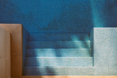 Top view of tiled bottom and steps in swimming pool with clean blue water