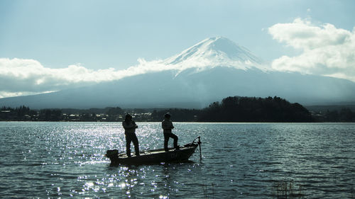 People in boat on water against sky