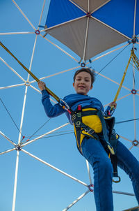 Low angle view of boy on swing against clear sky