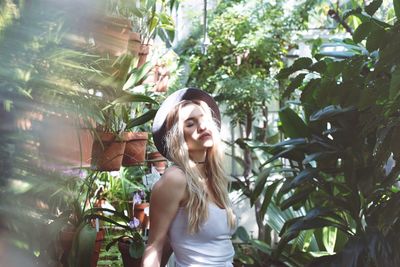 Portrait of young woman standing against plants